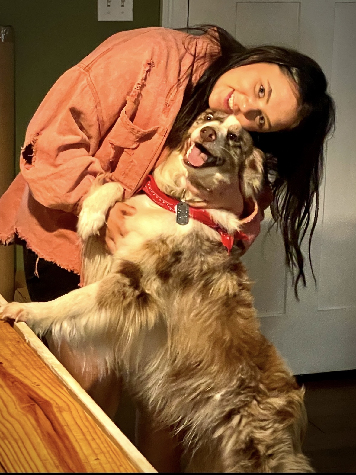 Smiling woman hugging her Australian shepherd emotional support dog.