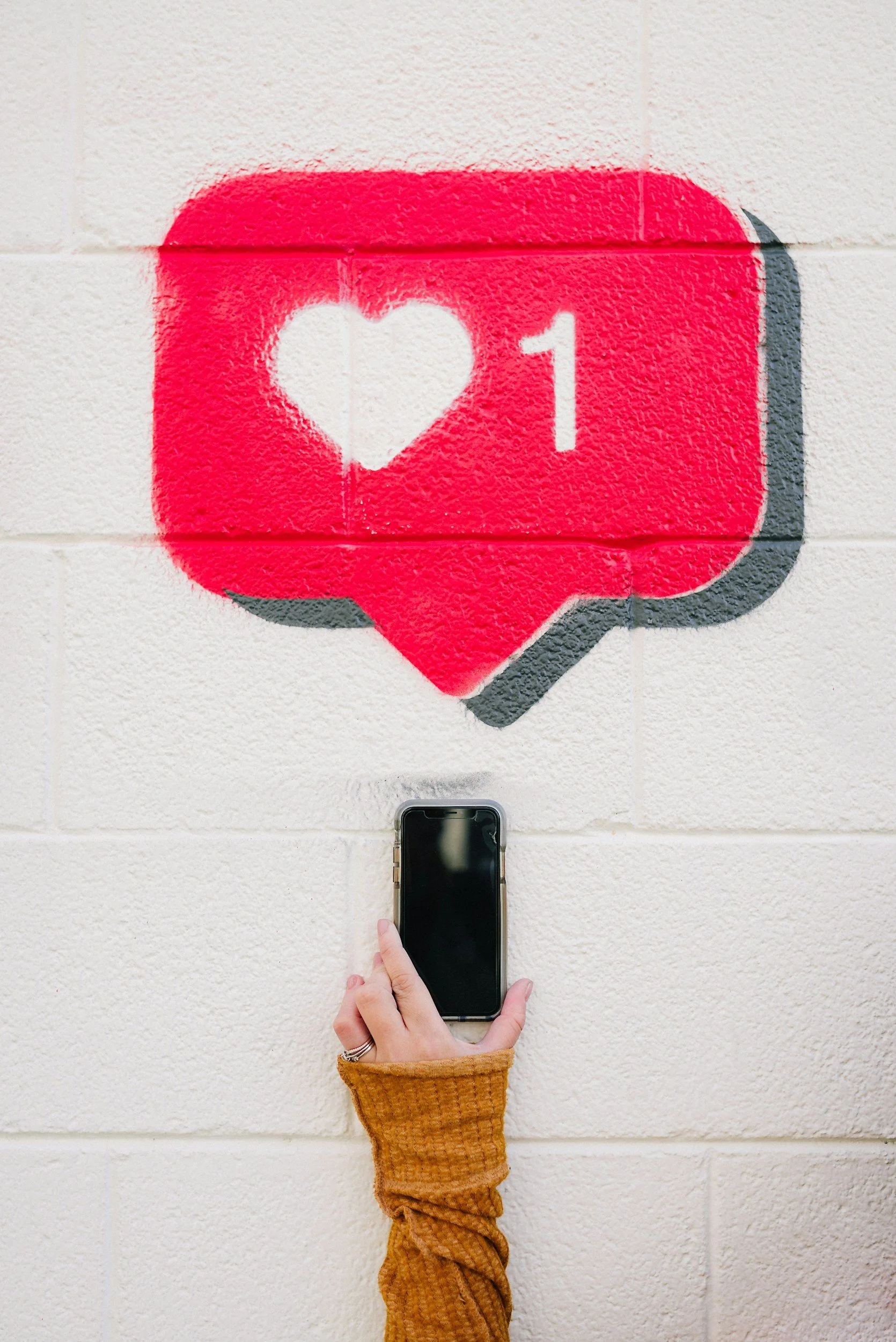 Person holding a smartphone beneath a painted social media like notification